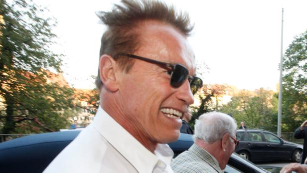 Arnold Schwarzenegger lächelt mit Sonnenbrille im Freien.