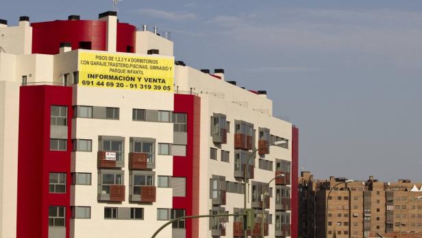 Ein Wohngebäude mit einem Werbebanner für Wohnungen mit Garage, Pool und Kinderspielplatz.