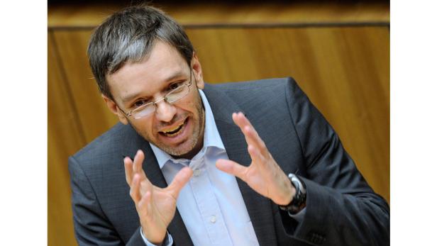 Ein Mann mit Brille gestikuliert mit beiden Händen.
