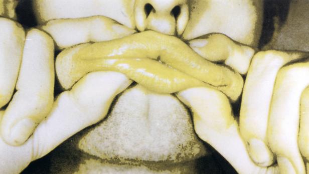 Nahaufnahme von einem Gesicht, dessen Mund von Händen verzerrt wird.