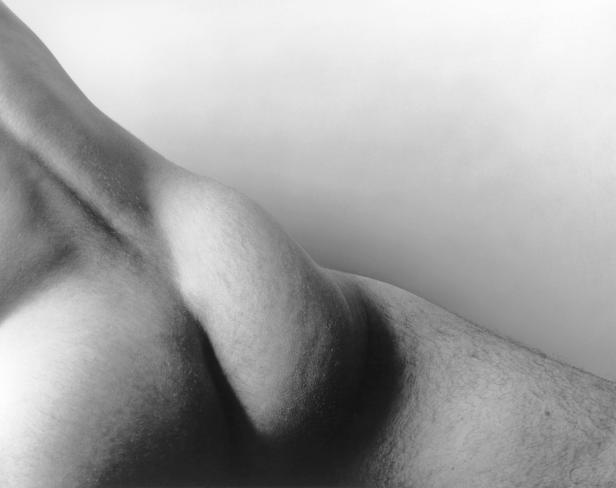 Detailaufnahme der Schulter und des Halses einer Person in Schwarzweiß.