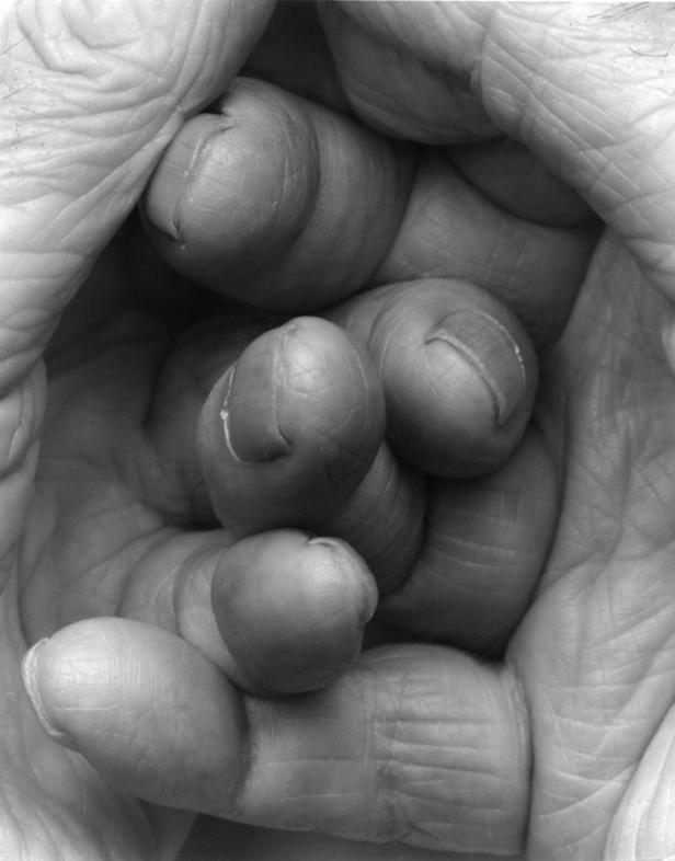 Eine Hand umfasst ihre eigenen Finger in einer Nahaufnahme.