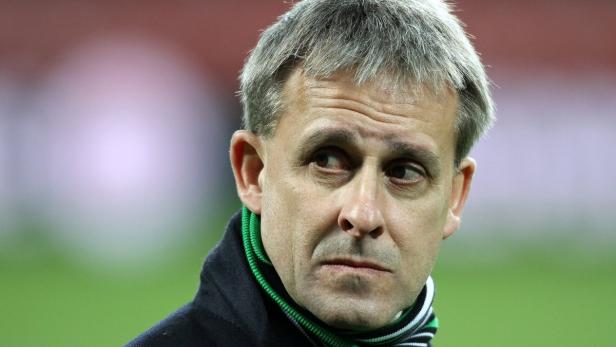 Ein Mann mit grauem Haar und einem Schal blickt zur Seite.