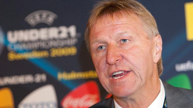 Ein Mann mit blonden Haaren spricht vor einem Hintergrund mit Logos.