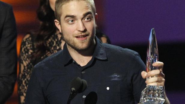 Robert Pattinson hält eine Auszeichnung in der Hand.