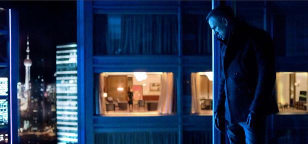 Daniel Craig steht vor einem Fenster mit Blick auf die Skyline von Shanghai.