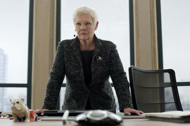 Judi Dench steht an einem Schreibtisch in einem Büro.