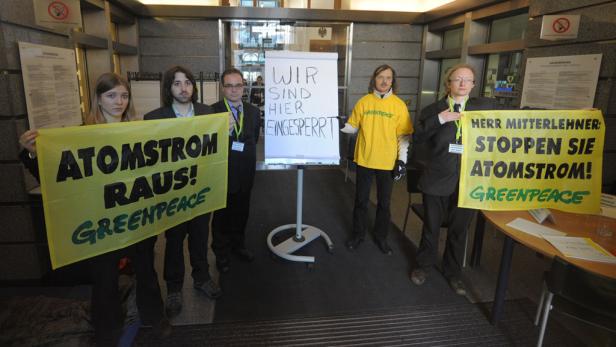 Aktivisten demonstrieren mit Transparenten gegen Atomstrom vor einem Gebäude.