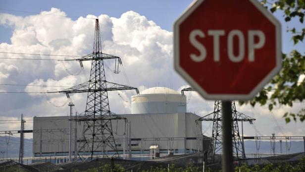 Ein Stoppschild vor einem Atomkraftwerk und Strommasten.