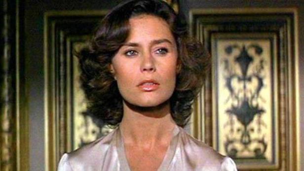 Jacqueline Bisset vor zwei gerahmten Bildern.