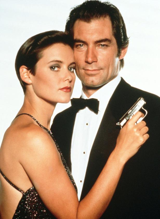 Timothy Dalton als James Bond mit einer Frau, die eine Waffe hält.