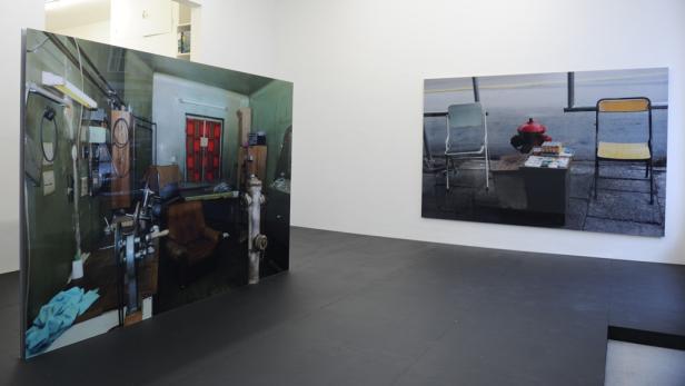 In einer Galerie sind zwei großformatige Fotografien ausgestellt.