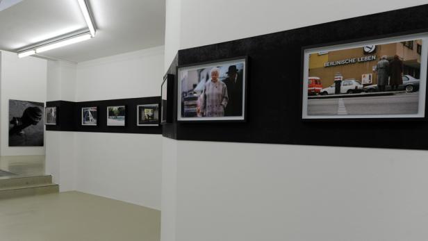 Ausstellung mit Fotografien an einer schwarz-weiß gestreiften Wand.