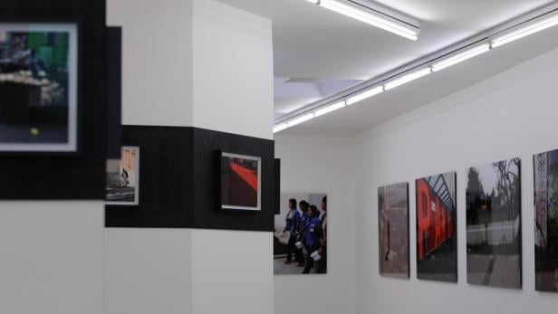 Eine Ausstellung mit Fotografien in einer Galerie mit weiß gestrichenen Wänden.