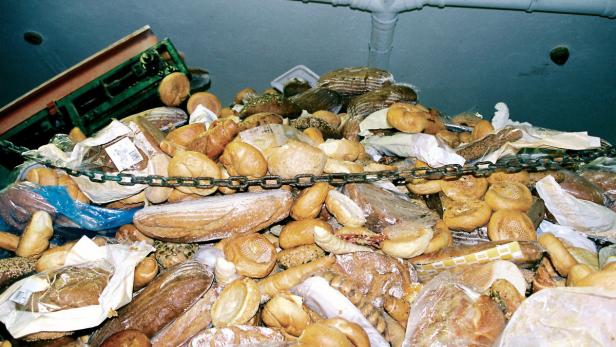 Ein großer Haufen Brot und Brötchen, teilweise in Plastik verpackt, liegt unter einer Decke mit Rohren.