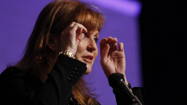 Sarah Ferguson gestikuliert während einer Rede vor einem Mikrofon.
