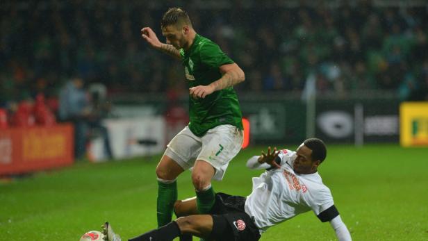 Zwei Fußballspieler kämpfen um den Ball auf dem Spielfeld.