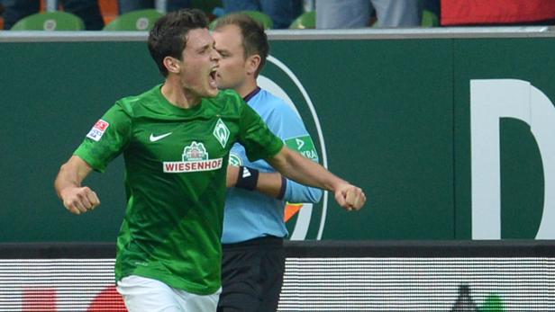 Ein Fußballspieler in Grün jubelt auf dem Spielfeld.