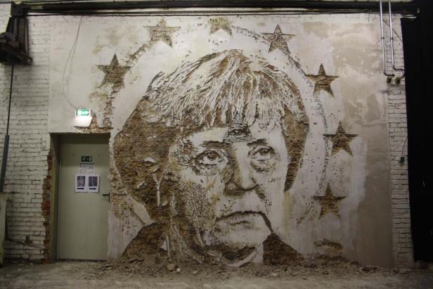 Ein Wandbild von Angela Merkel mit einem Heiligenschein aus Sternen.