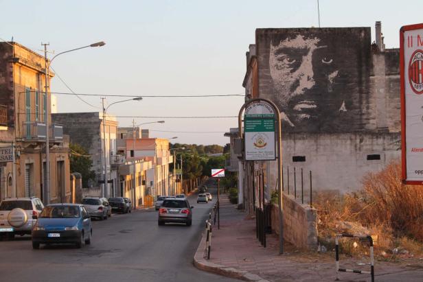 Blick auf eine Straße in Grottaglie mit einem großen Wandgemälde an einem Gebäude.