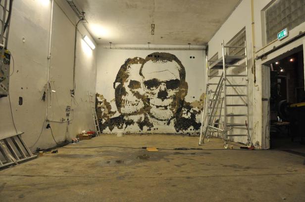 In einem Raum befindet sich ein Wandgemälde, das ein Gesicht und einen Schädel darstellt.