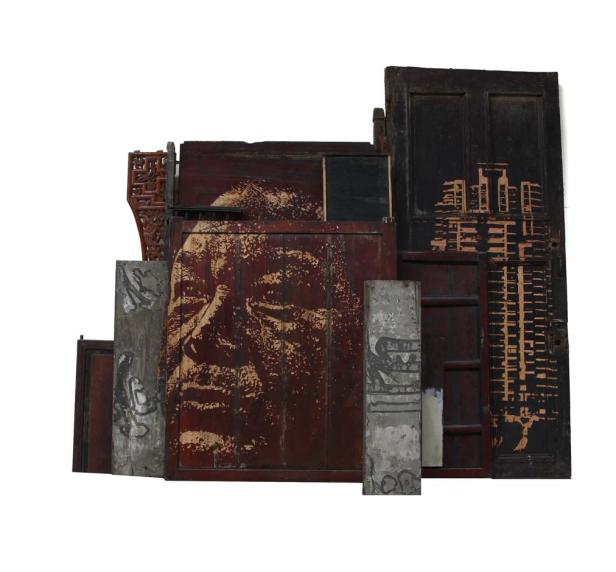 Eine Assemblage aus alten Türen und Betonstücken, bemalt mit einem Gesicht und einer Skyline.