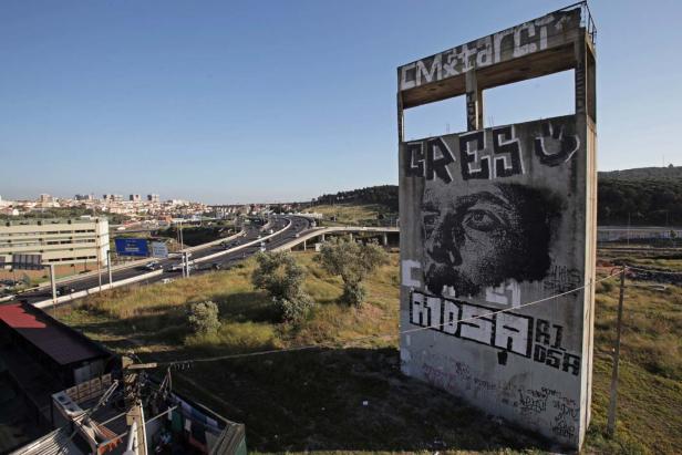 Ein Betongebäude mit Graffiti steht neben einer Autobahn in einer städtischen Landschaft.