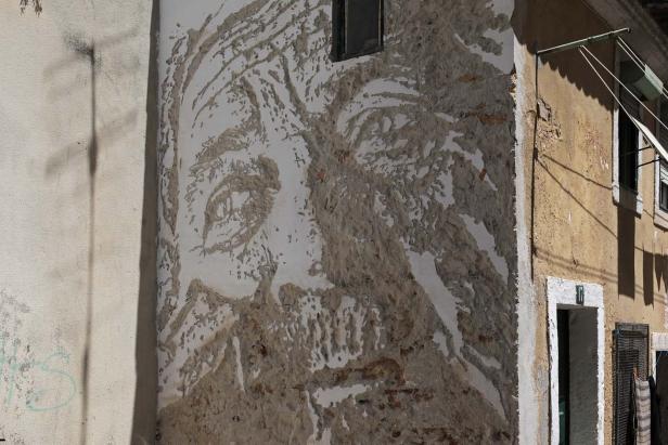 Ein an eine Hauswand gemaltes Porträt einer Person.