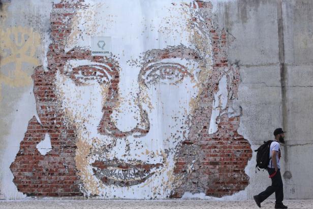 Ein Mann geht an einem Wandgemälde vorbei, das ein Gesicht darstellt.