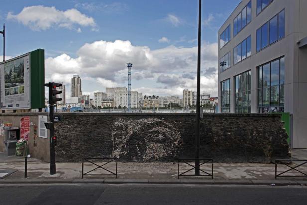 Eine Steinmauer in Paris mit Blick auf die Stadtlandschaft im Hintergrund.