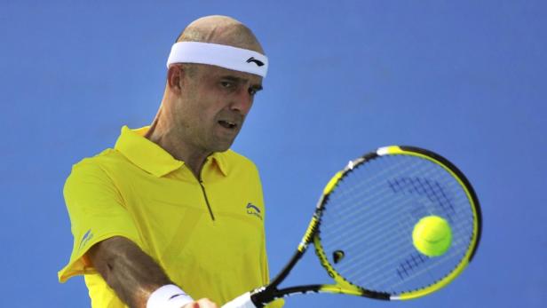 Ein Tennisspieler mit Stirnband schlägt einen Ball mit seinem Schläger.