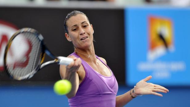 Eine Tennisspielerin schlägt einen Ball mit ihrem Schläger.