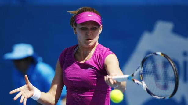 Eine Tennisspielerin schlägt einen gelben Tennisball mit ihrem Schläger.