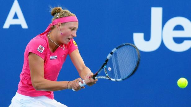 Eine Tennisspielerin schlägt einen Ball mit ihrem Schläger.