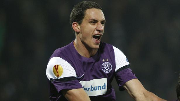 Ein Fußballspieler in lila Trikot jubelt mit geöffnetem Mund.