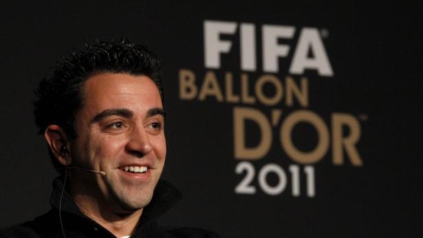 Xavi Hernández lächelt vor dem Hintergrund des FIFA Ballon D'Or 2011 Logos.