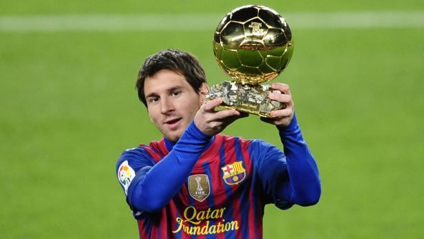 Lionel Messi hält den Ballon d'Or Pokal in seinen Händen.