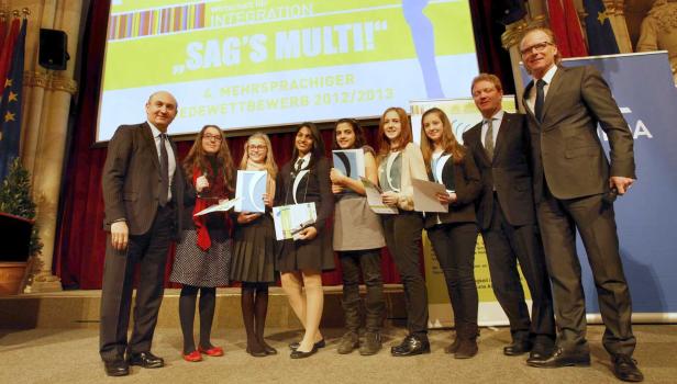 Eine Gruppe von Schülerinnen und zwei Männer posieren auf einer Bühne für den Wettbewerb „Sag’s Multi!“.