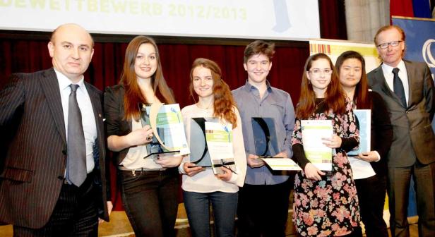 Eine Gruppe junger Preisträger posiert mit Urkunden und zwei Männern im Anzug.