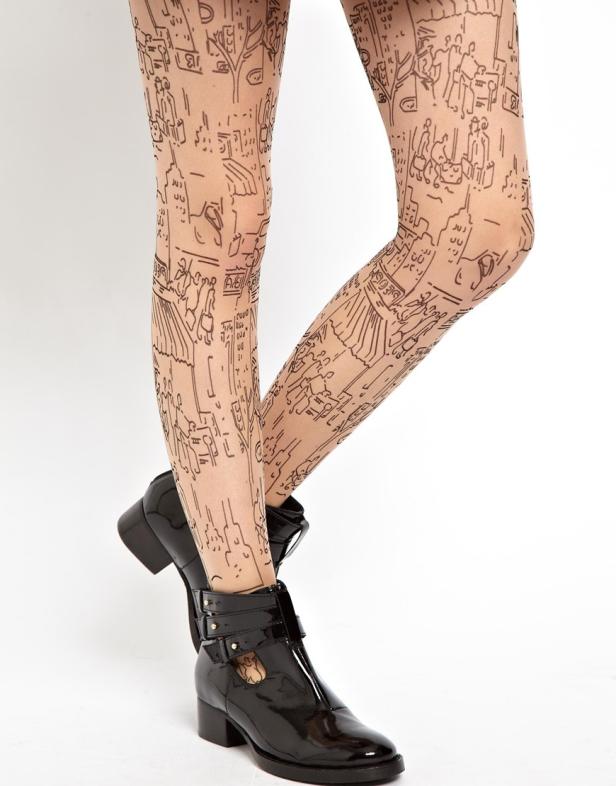 Beine mit einer Strumpfhose mit Stadtszenen-Muster und schwarzen Stiefeletten.