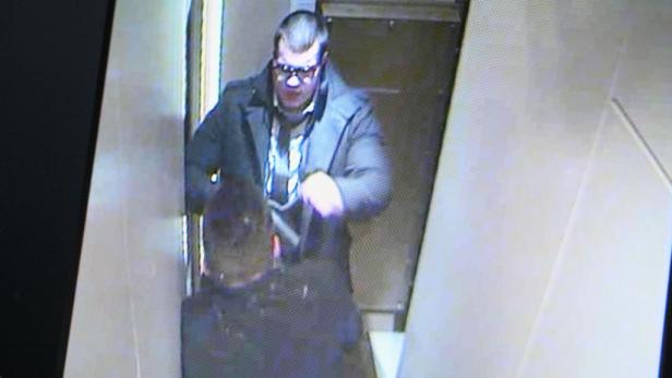 Ein Mann mit Brille und Mantel steht in einer Türöffnung.