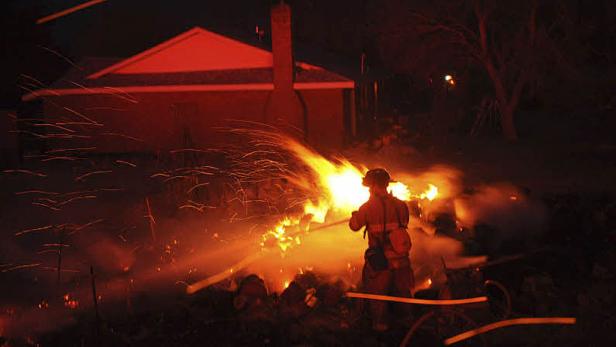 Ein Feuerwehrmann bekämpft einen Brand in der Nacht.