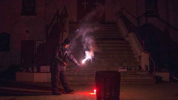 Eine Person zündet vor einer Kirche Feuerwerkskörper an.