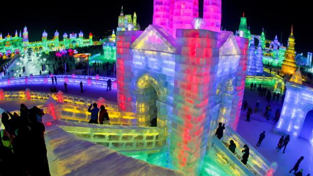 Eine farbenfrohe Eisstadt mit vielen Besuchern bei Nacht.