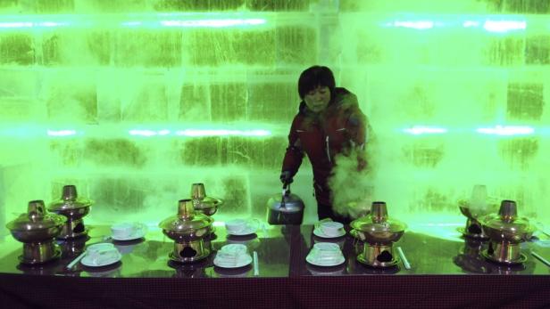 Eine Frau gießt Wasser in einem Restaurant mit Eiswänden in Kochtöpfe.