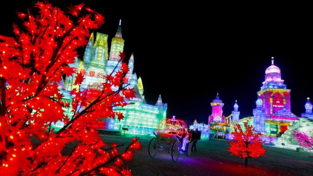 Nachts erstrahlen Eispaläste und eine Kutsche in bunten Lichtern.