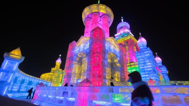 Eine farbenfrohe Eisburg leuchtet nachts.