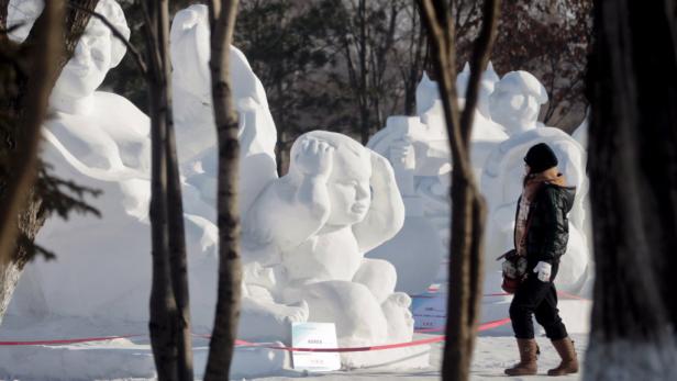 Eine Frau betrachtet Schneeskulpturen auf einem Festival.