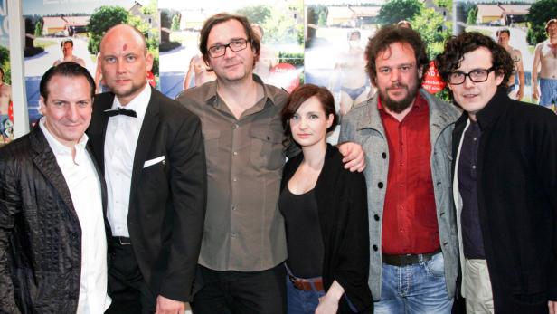 Eine Gruppe von sechs Personen posiert vor einem Filmposter.