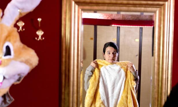 Eine Frau hält ein gelbes Hasenkostüm vor einem Spiegel.